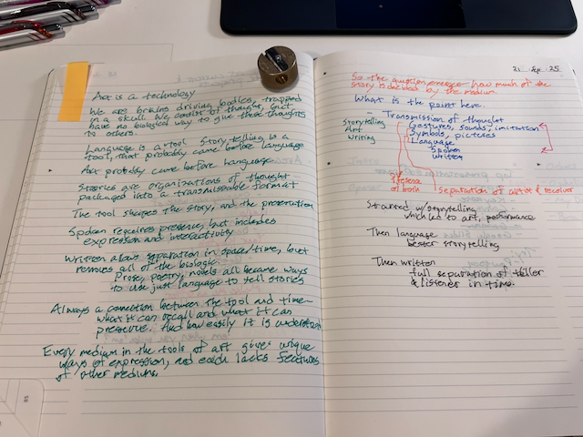Photo of an opened notebook, with both pages covered with writing in five different colors.